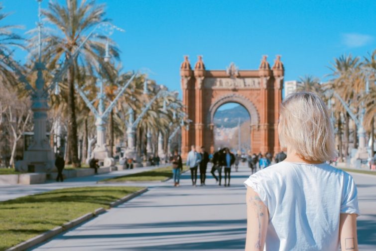 Eine junge Frau blickt auf den Triumphbogen in Barcelona, Spanien. Perfekt für alle, die einen Umzug nach Spanien planen oder sich für die spanische Kultur und Architektur interessieren. Ideal, um die Schönheit Barcelonas zu entdecken.