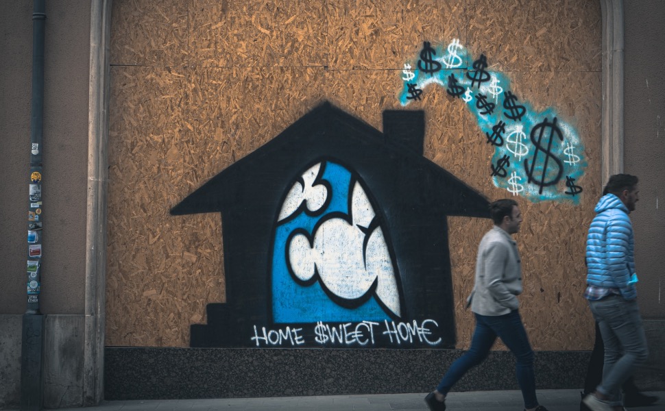 Graffiti eines Hauses mit dem Schriftzug „Home Sweet Home“, davor zwei Passanten