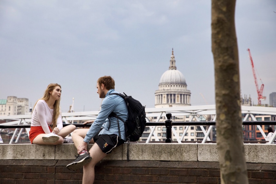 Entdecken Sie romantische Momente vor der ikonischen Kulisse der St. Paul's Cathedral in London. Dieses Bild zeigt ein junges Paar, das auf einer Mauer sitzt und die Aussicht auf die Stadt genießt, ideal für Reise- und Kulturliebhaber.